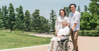車いすの高齢の女性と公園を散歩する介護スタッフ