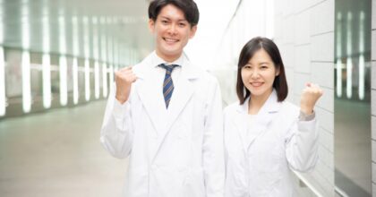 白衣を着て笑顔でガッツポーズをする2人の医師